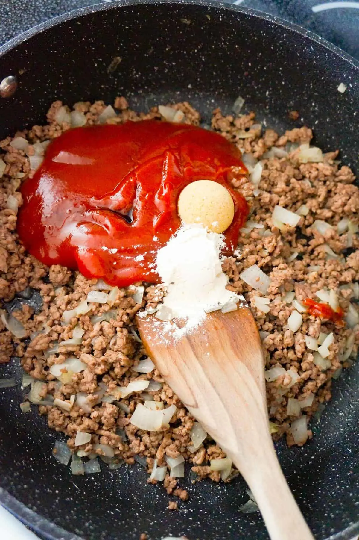 ketchup, brown sugar and onion powder on top of cooked ground beef in a saute pan
