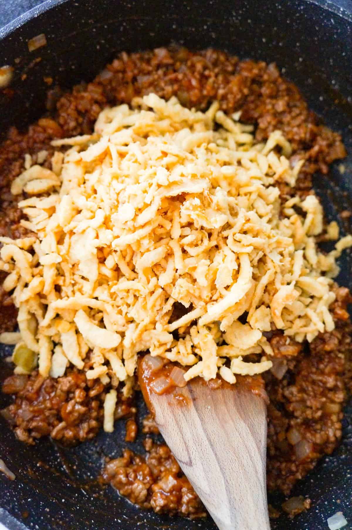 French's crispy fried onions on top of ground beef sloppy joe mixture in a saute pan