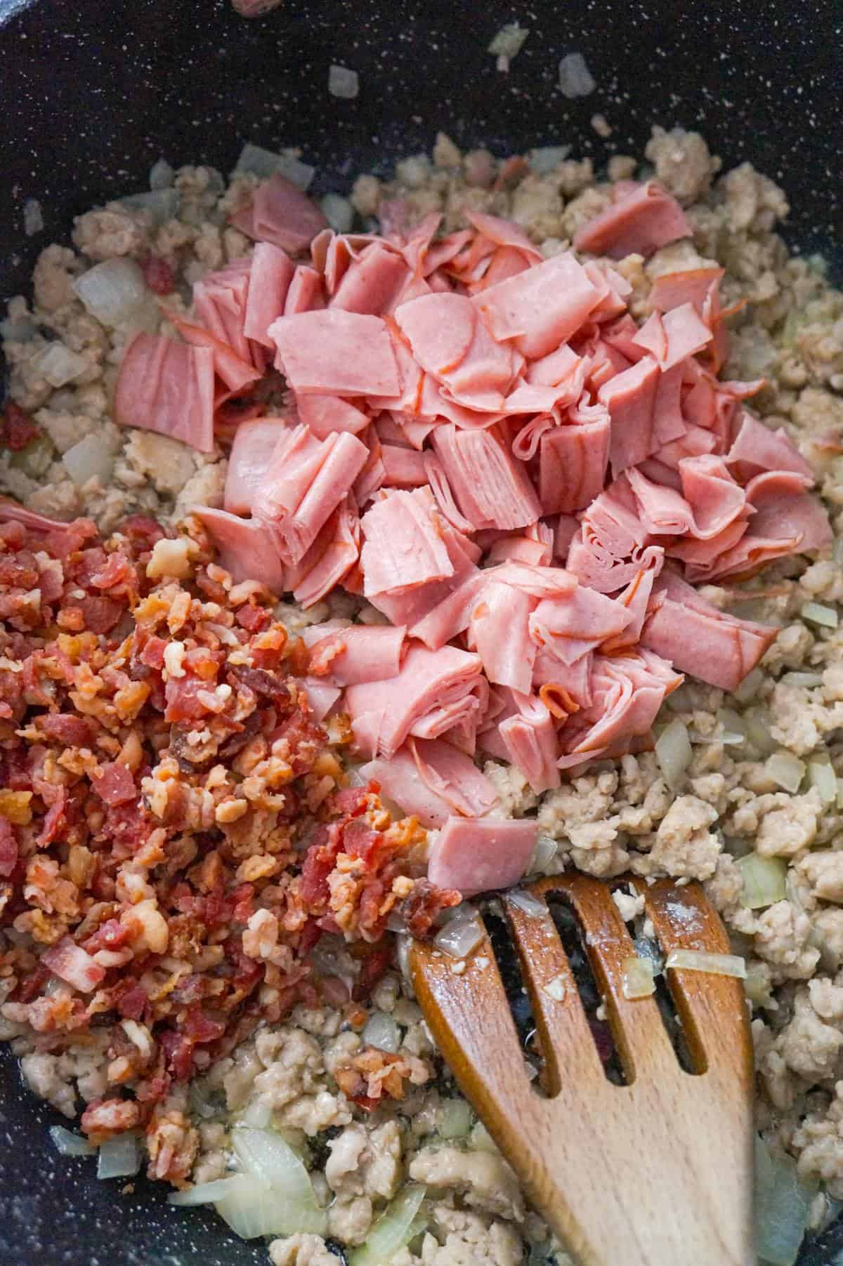 chopped ham and crumbled bacon on top of ground sausage meat in a saute pan
