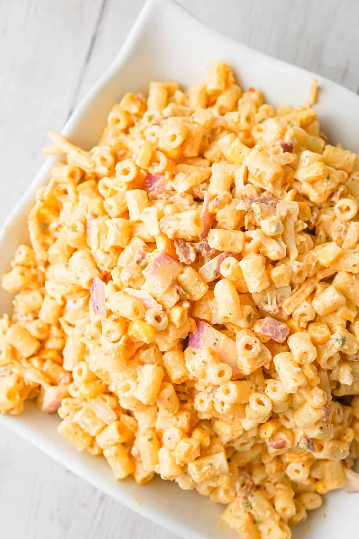 Cajun Macaroni Salad is a cold side dish recipe loaded with canned corn, crumbled bacon, diced red onions, shredded cheese and tossed in mayo and Cajun seasoning.