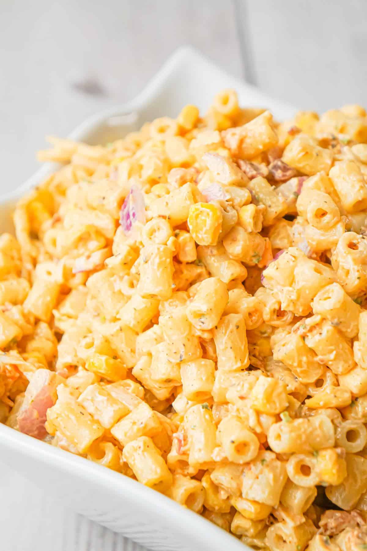 Cajun Macaroni Salad is a cold side dish recipe loaded with canned corn, crumbled bacon, diced red onions, shredded cheese and tossed in mayo and Cajun seasoning.