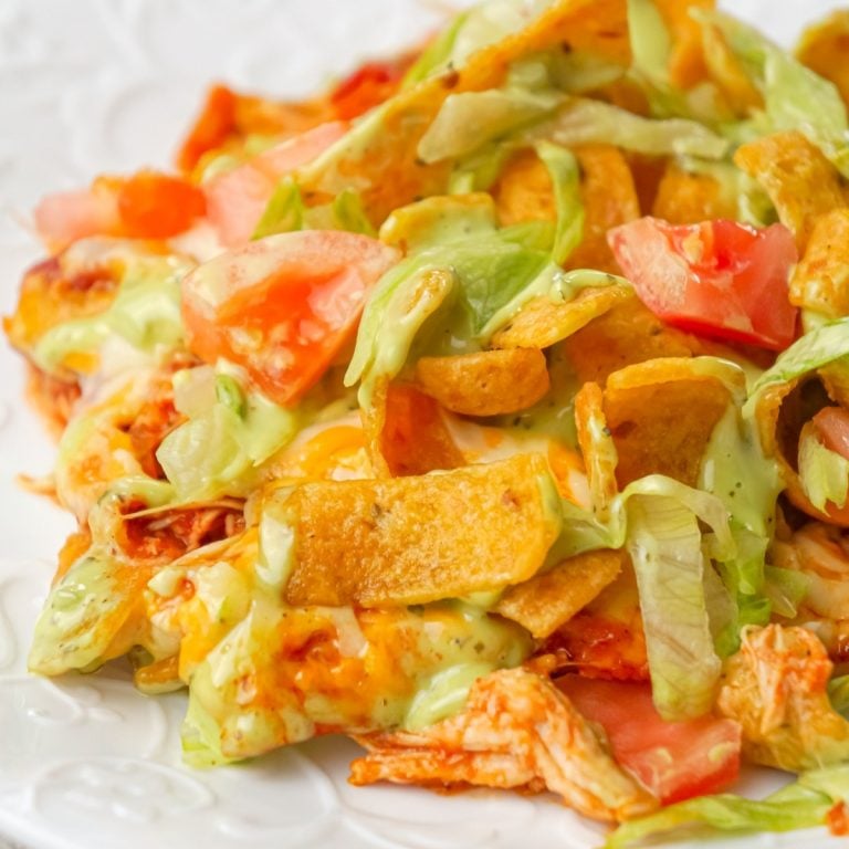 Chicken Taco Frito Pie is an easy weeknight dinner recipe made with shredded chicken tossed in salsa, taco seasoning and chili sauce and topped with cheese, Fritos corn chips, avocado dip, shredded lettuce and diced tomatoes.