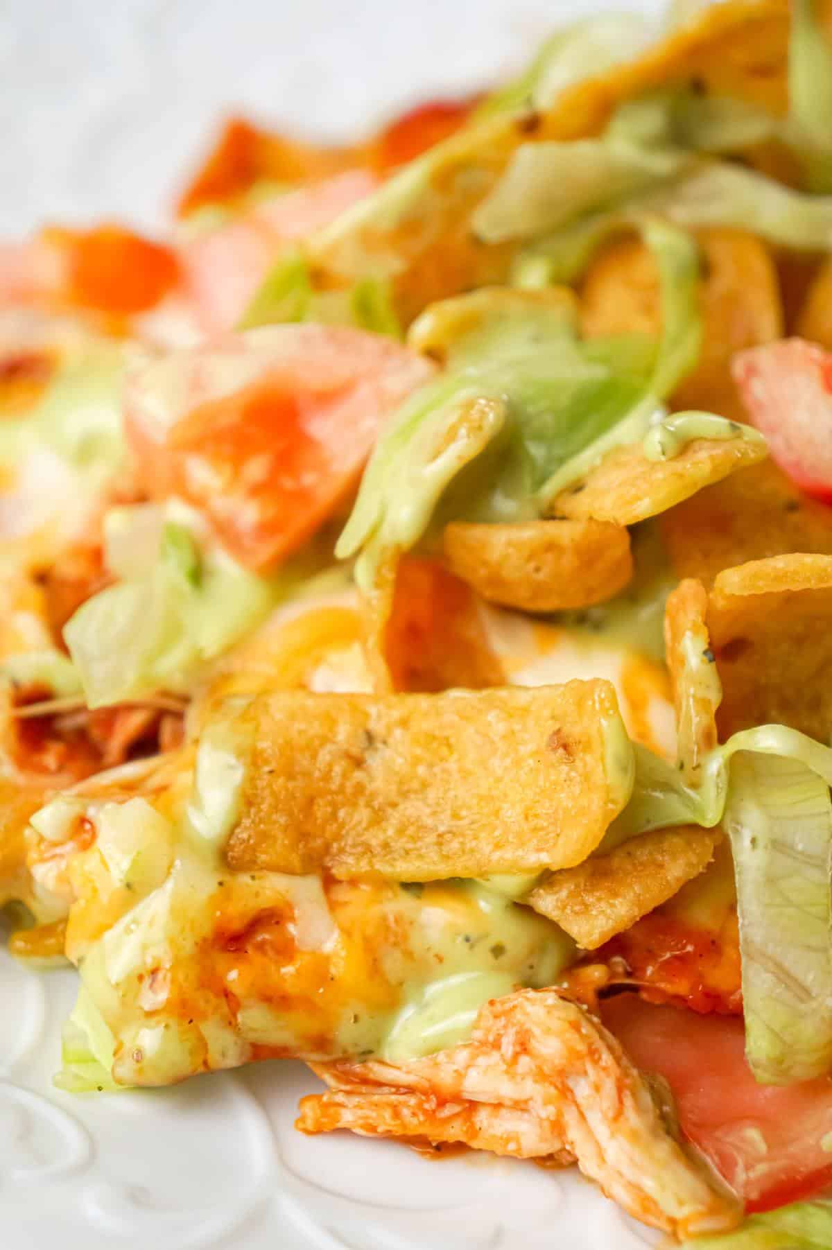 Chicken Taco Frito Pie is an easy weeknight dinner recipe made with shredded chicken tossed in salsa, taco seasoning and chili sauce and topped with cheese, Fritos corn chips, avocado dip, shredded lettuce and diced tomatoes.