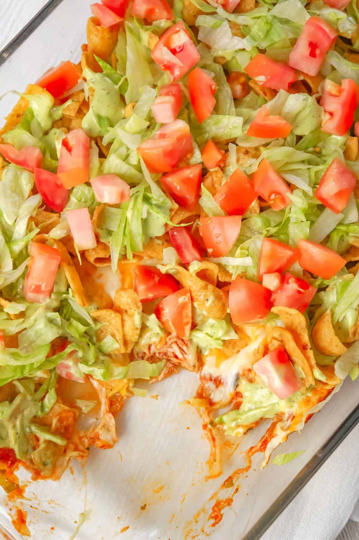 Chicken Taco Frito Pie is an easy weeknight dinner recipe made with shredded chicken tossed in salsa, taco seasoning and chili sauce and topped with cheese, Fritos corn chips, avocado dip, shredded lettuce and diced tomatoes.