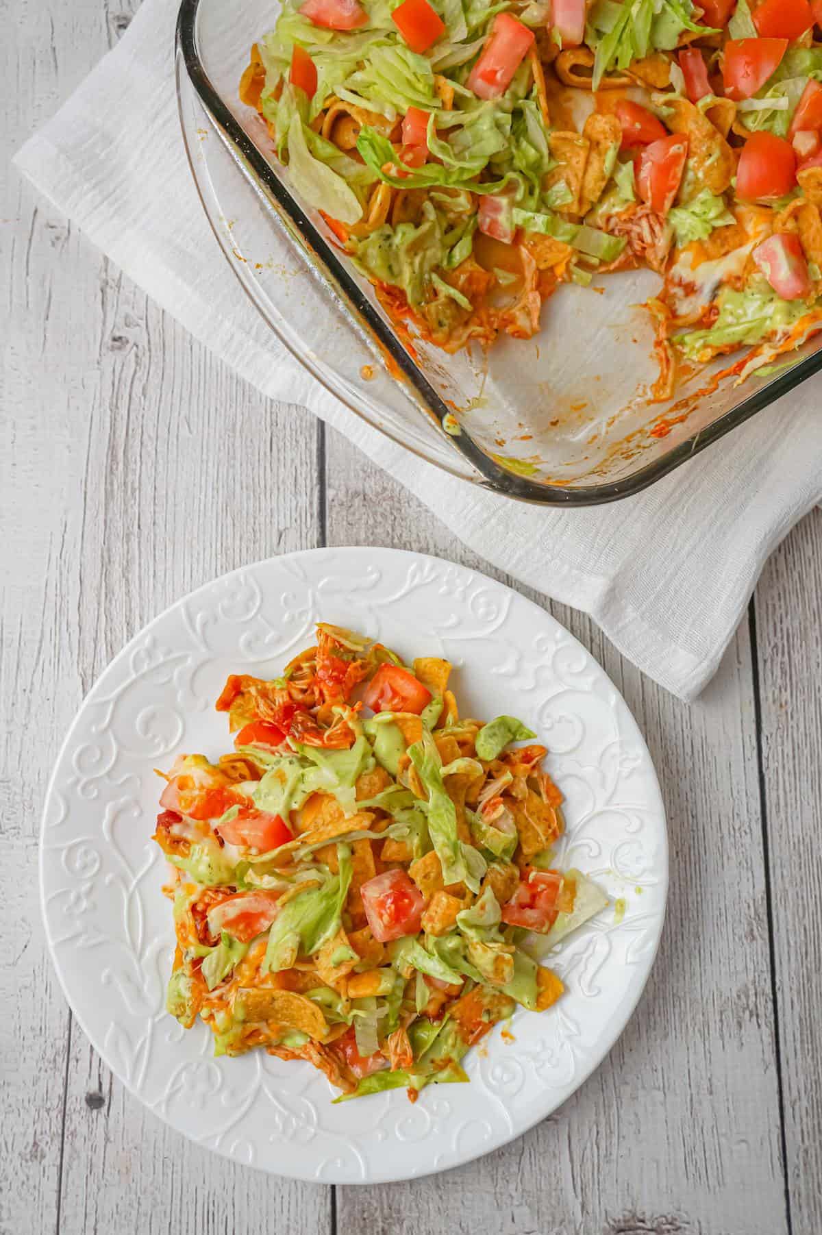 Chicken Taco Frito Pie is an easy weeknight dinner recipe made with shredded chicken tossed in salsa, taco seasoning and chili sauce and topped with cheese, Fritos corn chips, avocado dip, shredded lettuce and diced tomatoes.
