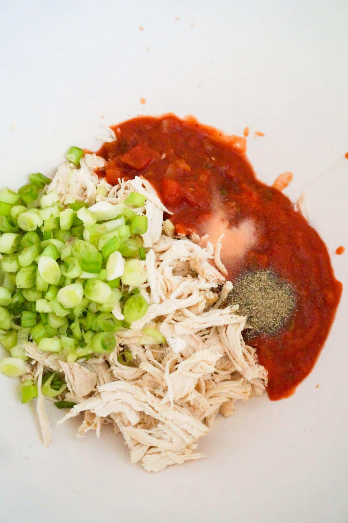chopped green onions, shredded chicken and salsa in a mixing bowl
