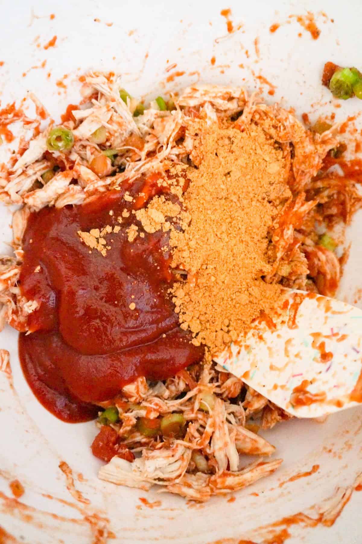 chili sauce and taco seasoning on top of shredded chicken and salsa mixture in a bowl