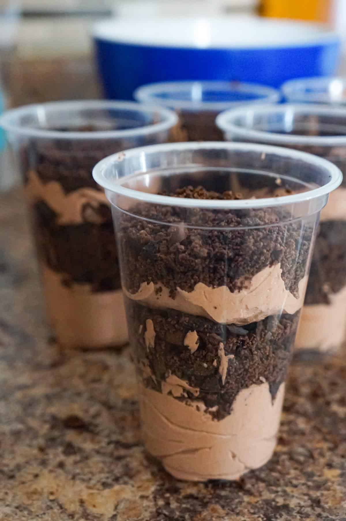 layers of pudding and cookie crumble in clear plastic cups