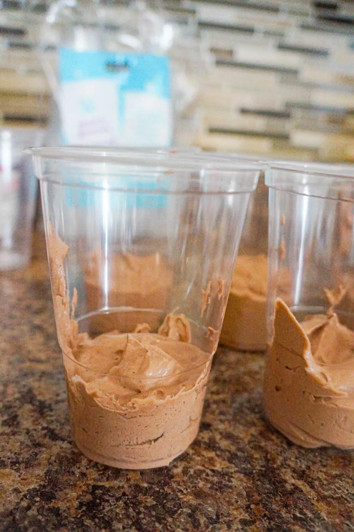 cool whip and chocolate pudding mixture in the bottom of clear plastic cups