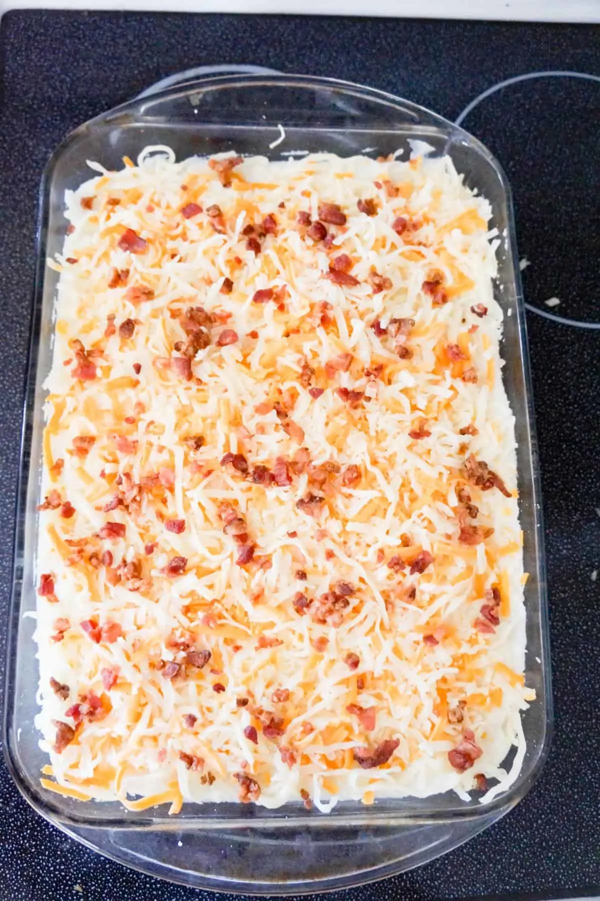 crumbled bacon and shredded cheese on top of shepherd's pie before baking