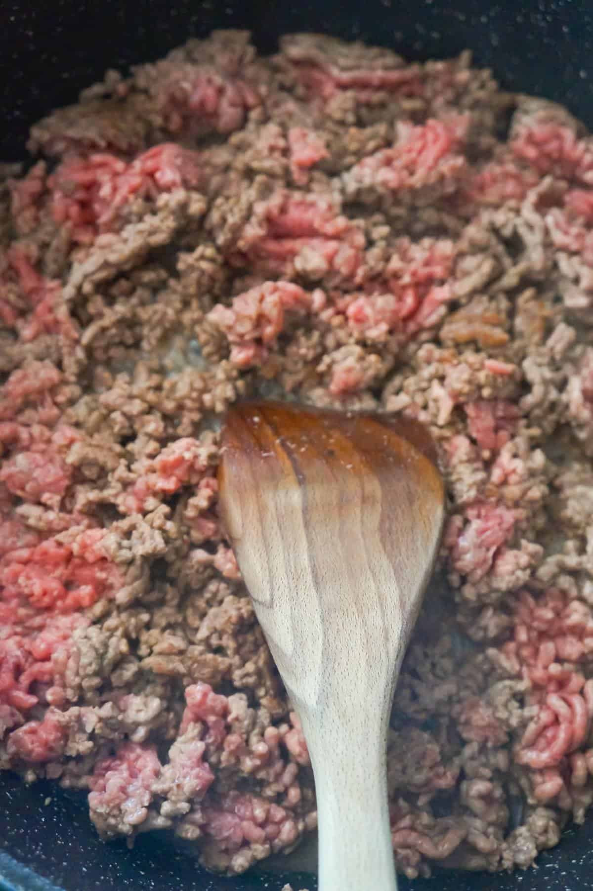 ground beef cooking in a large saute pan
