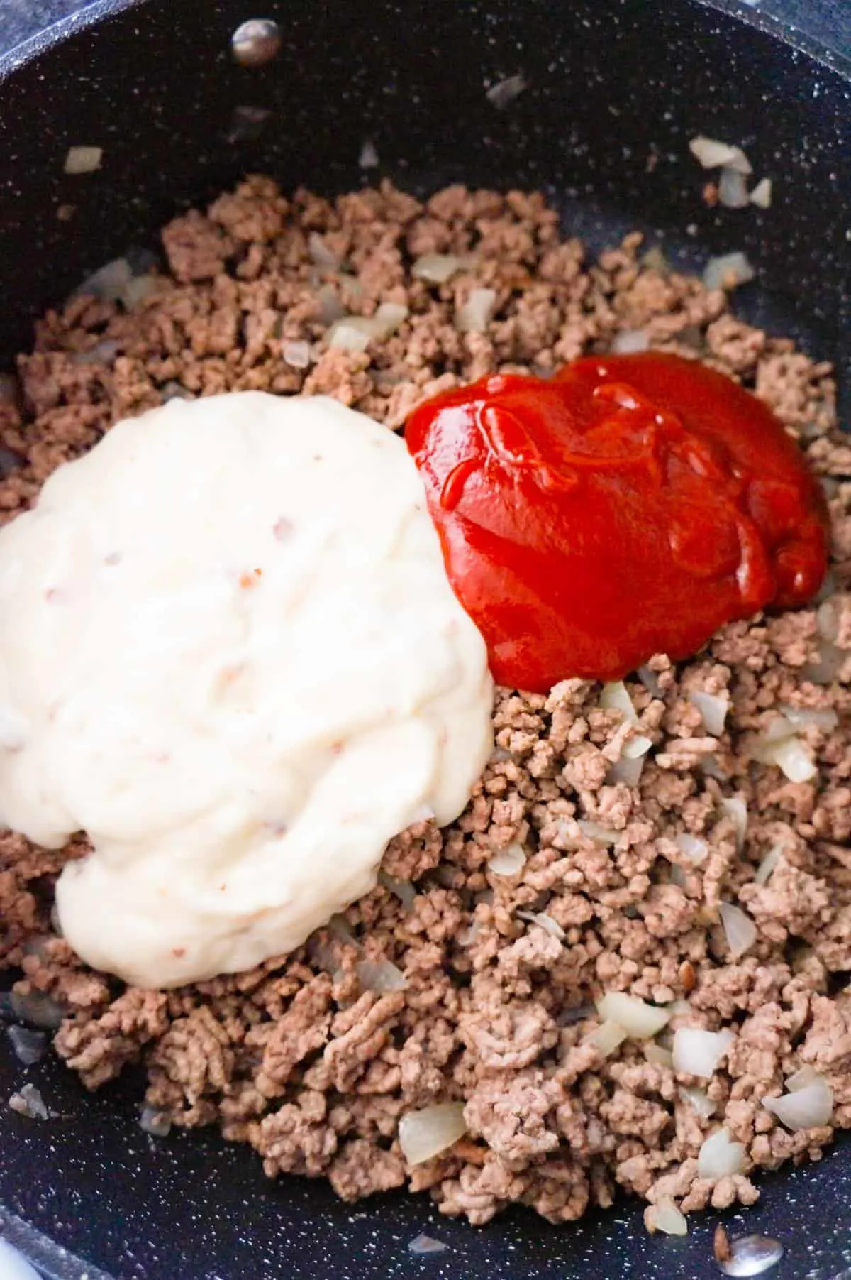 cream of bacon soup and ketchup on top of cooked ground beef in a large saute pan
