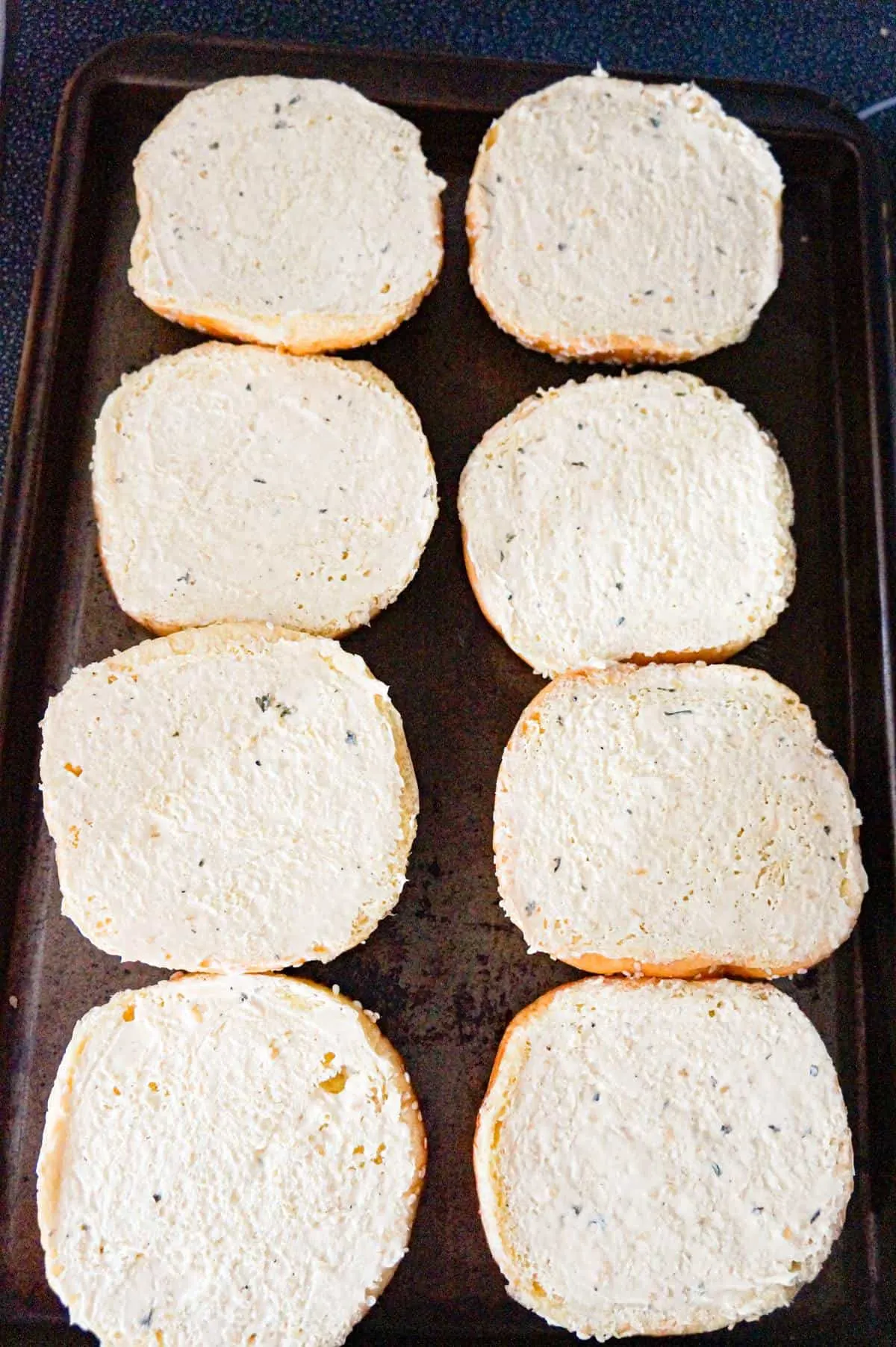 brioche buns in a single layer on a baking sheet spread with garlic margarine