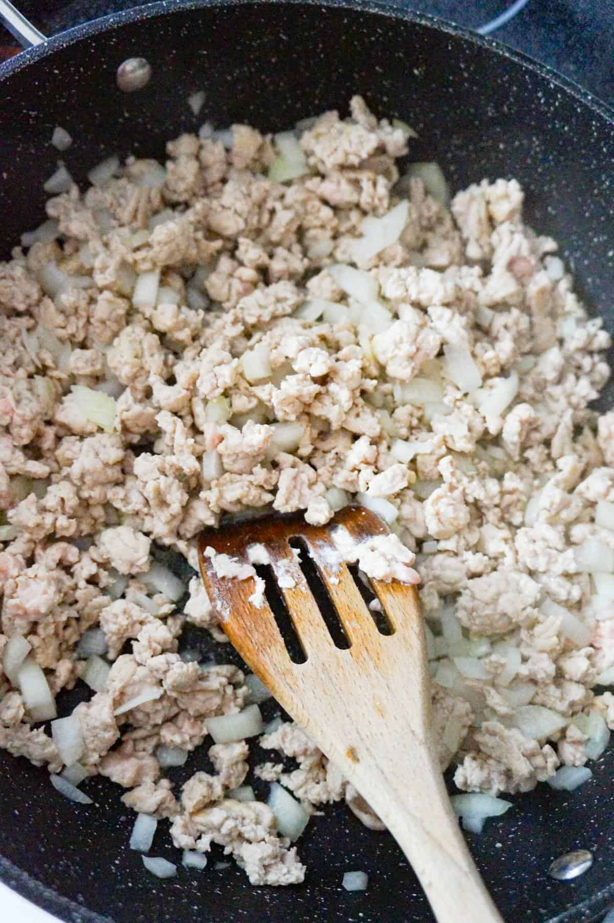 ground chicken and diced onions cooking in a saute pan