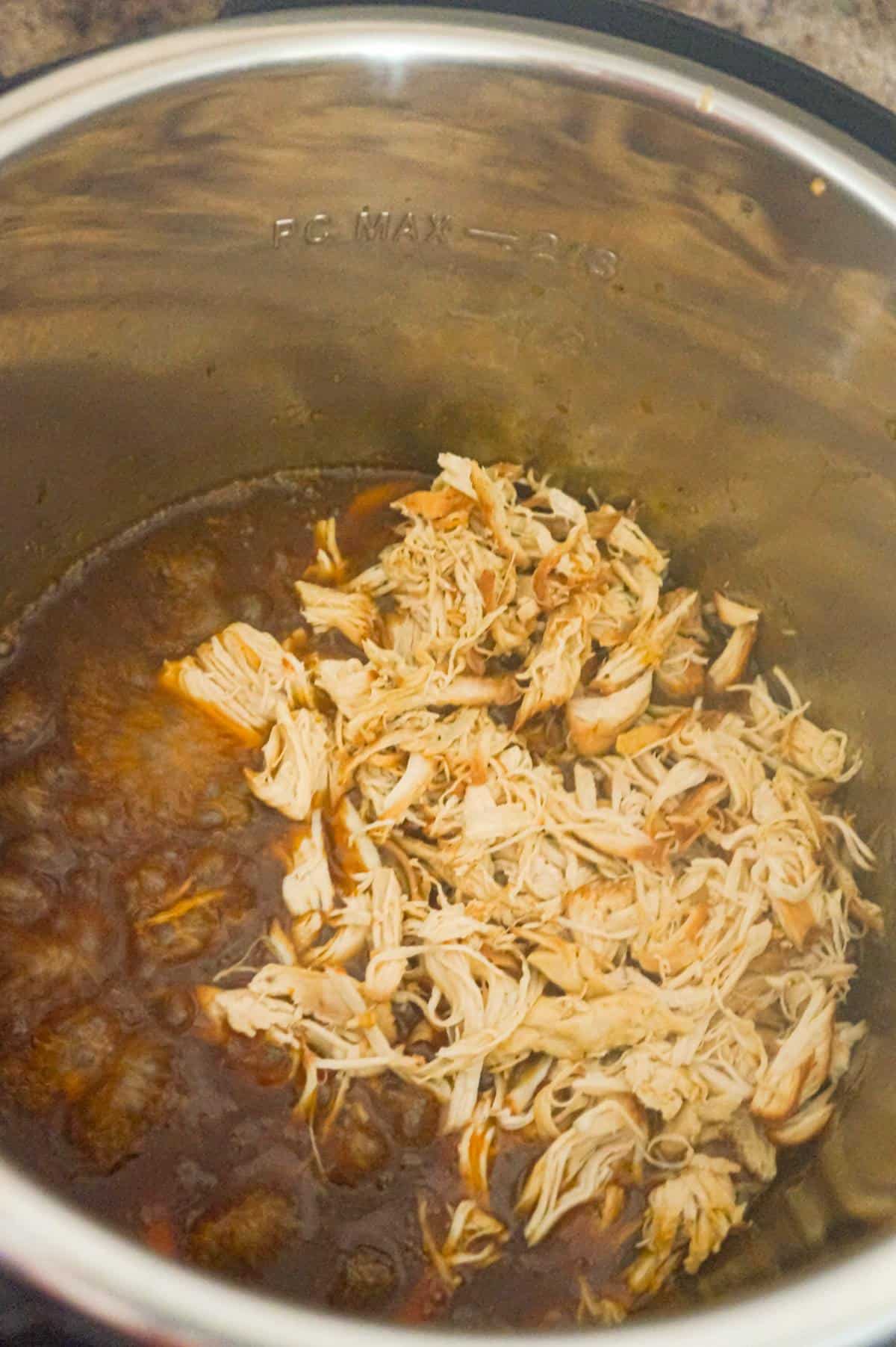 shredded chicken added to honey garlic sauce in an Instant Pot