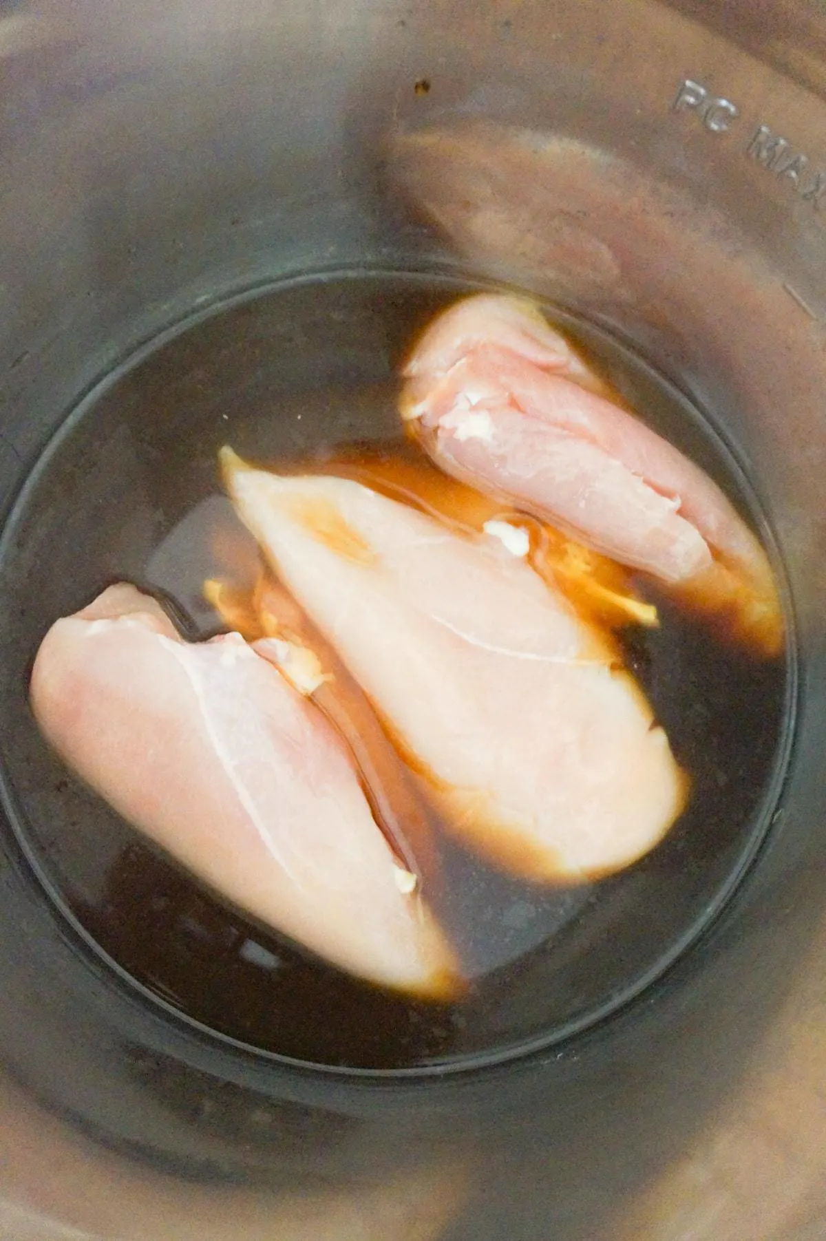raw chicken breasts in an Instant Pot with honey garlic sauce