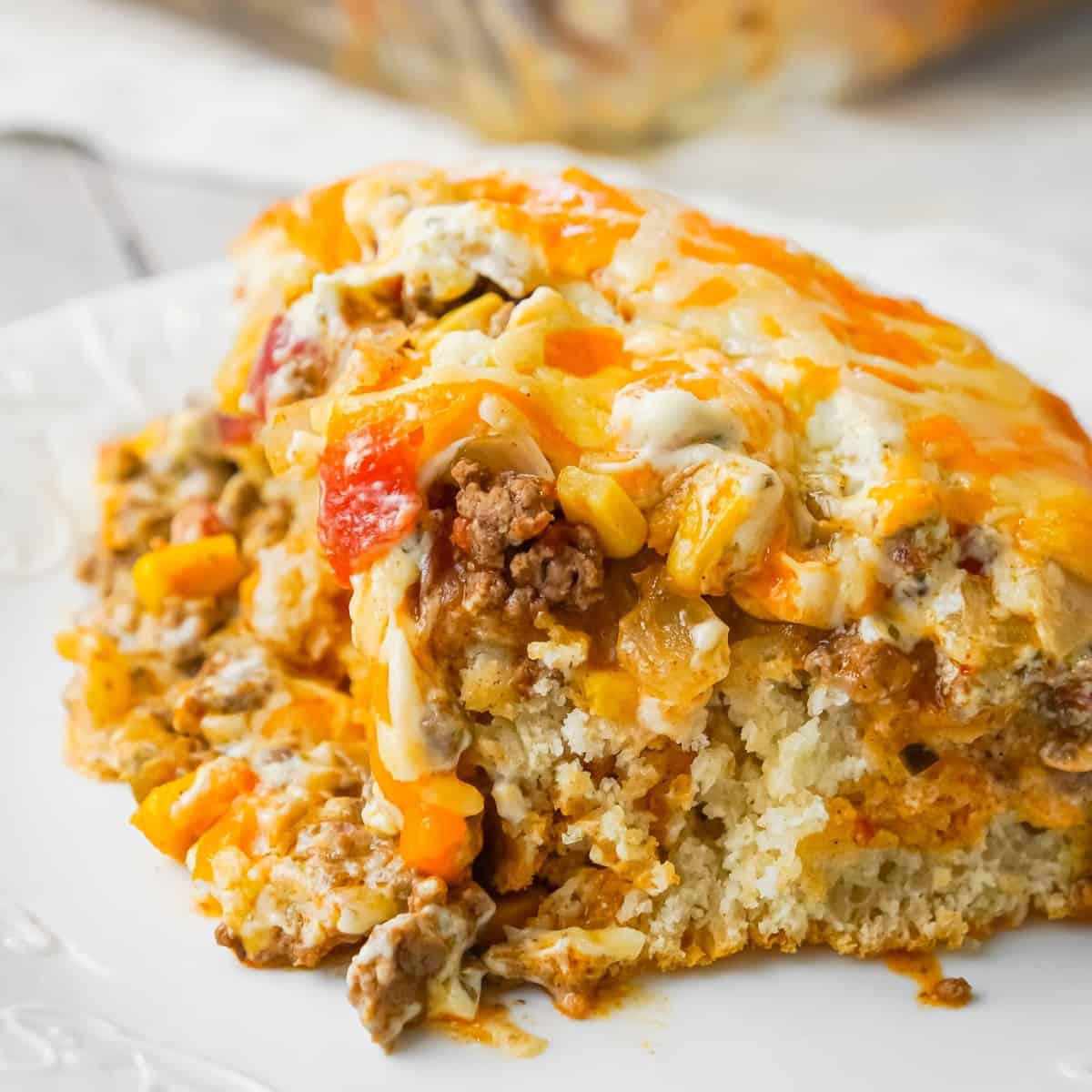 John Wayne Casserole is an easy ground beef casserole recipe with a biscuit base and loaded with diced tomatoes, corn, taco seasoning, cream cheese, mozzarella and cheddar.