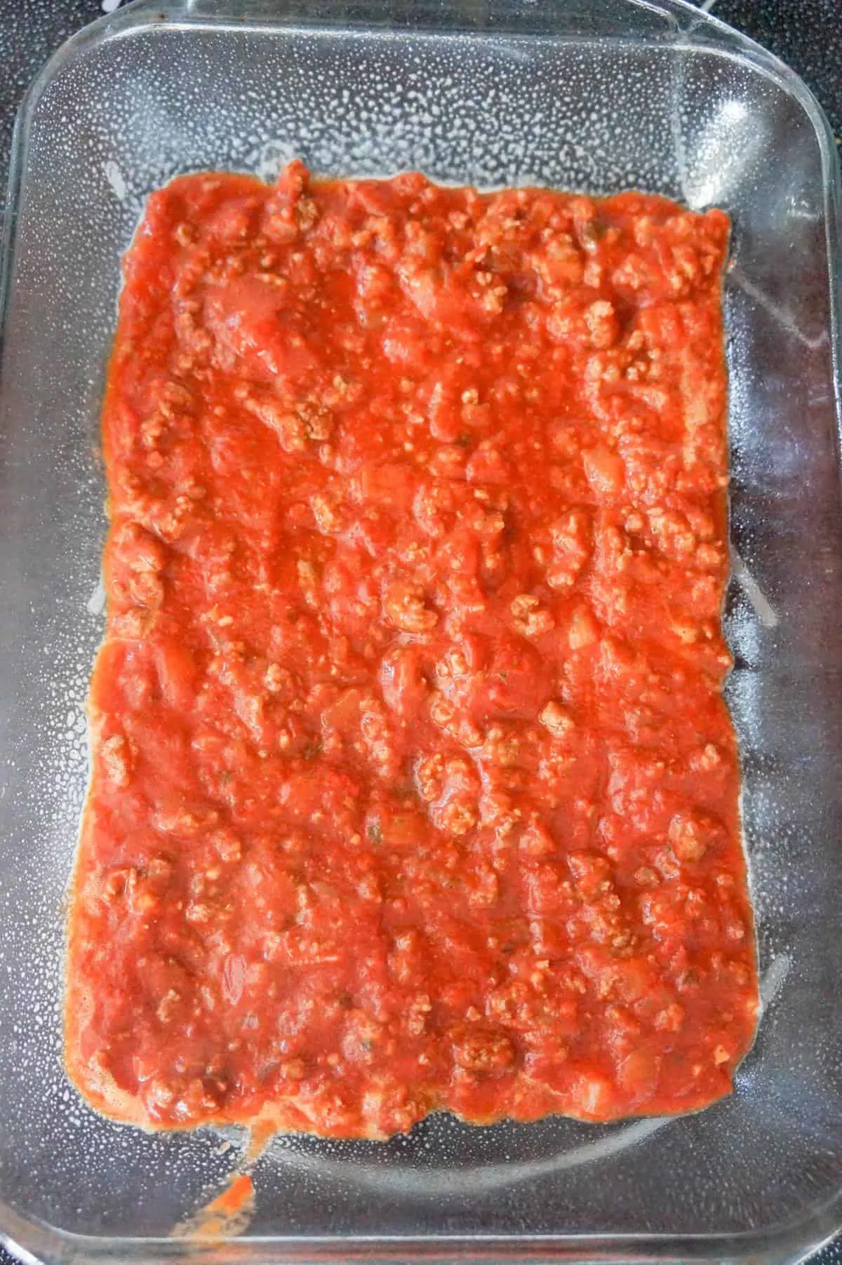ground beef and marinara sauce in the bottom of a baking dish