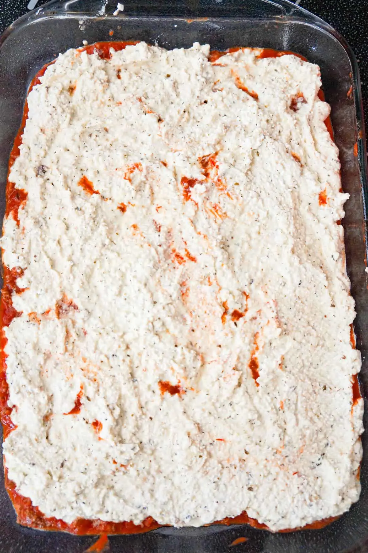 ricotta mixture on top of marinara in a baking dish