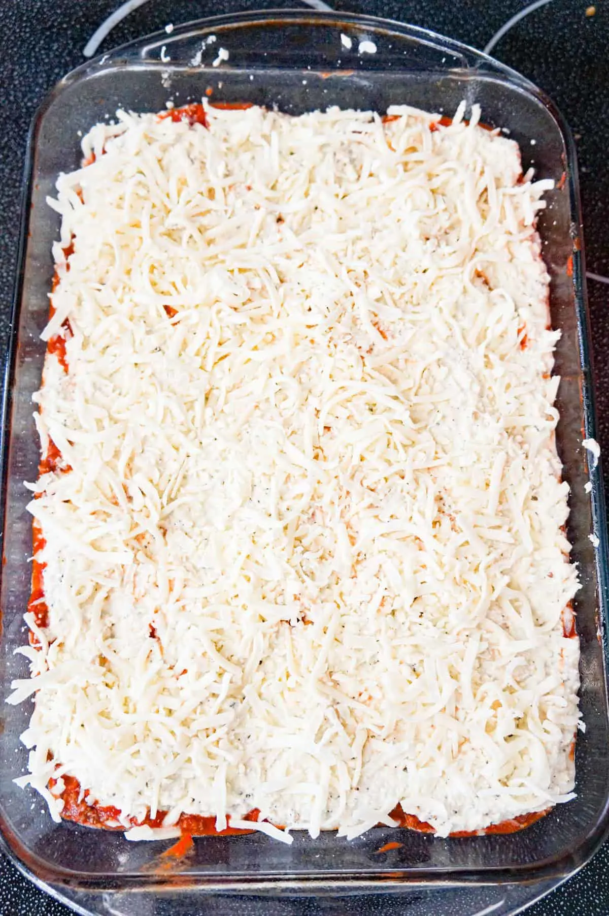 shredded mozzarella on top of ricotta mixture in a baking dish