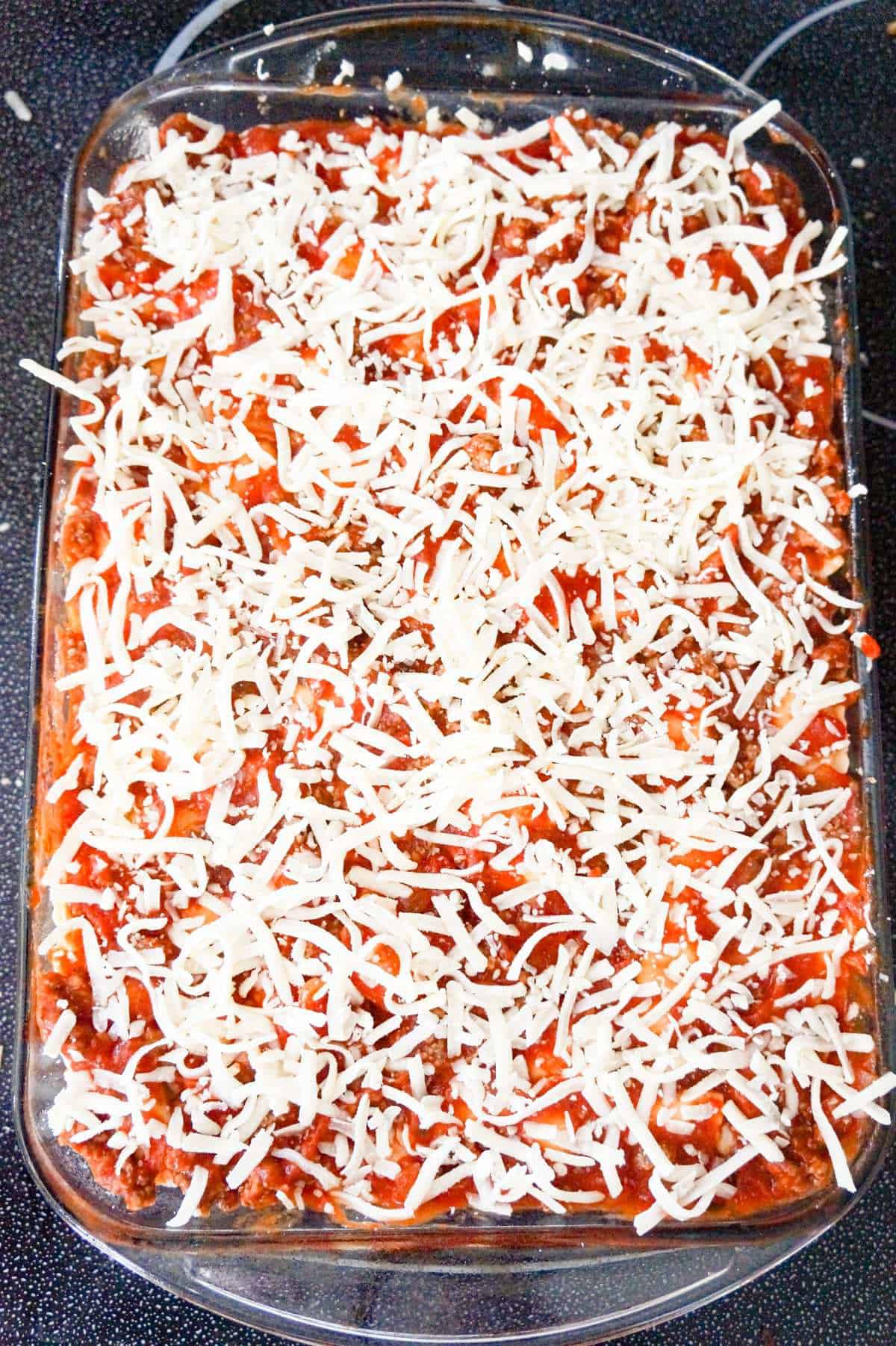 shredded mozzarella on top of ravioli lasagna before baking