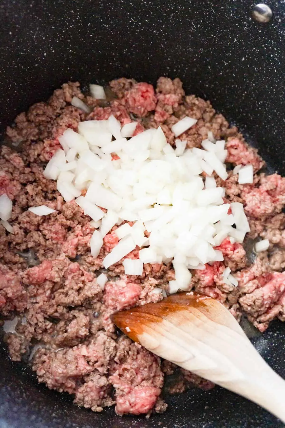 diced onions on top of ground beef cooking in a large pot
