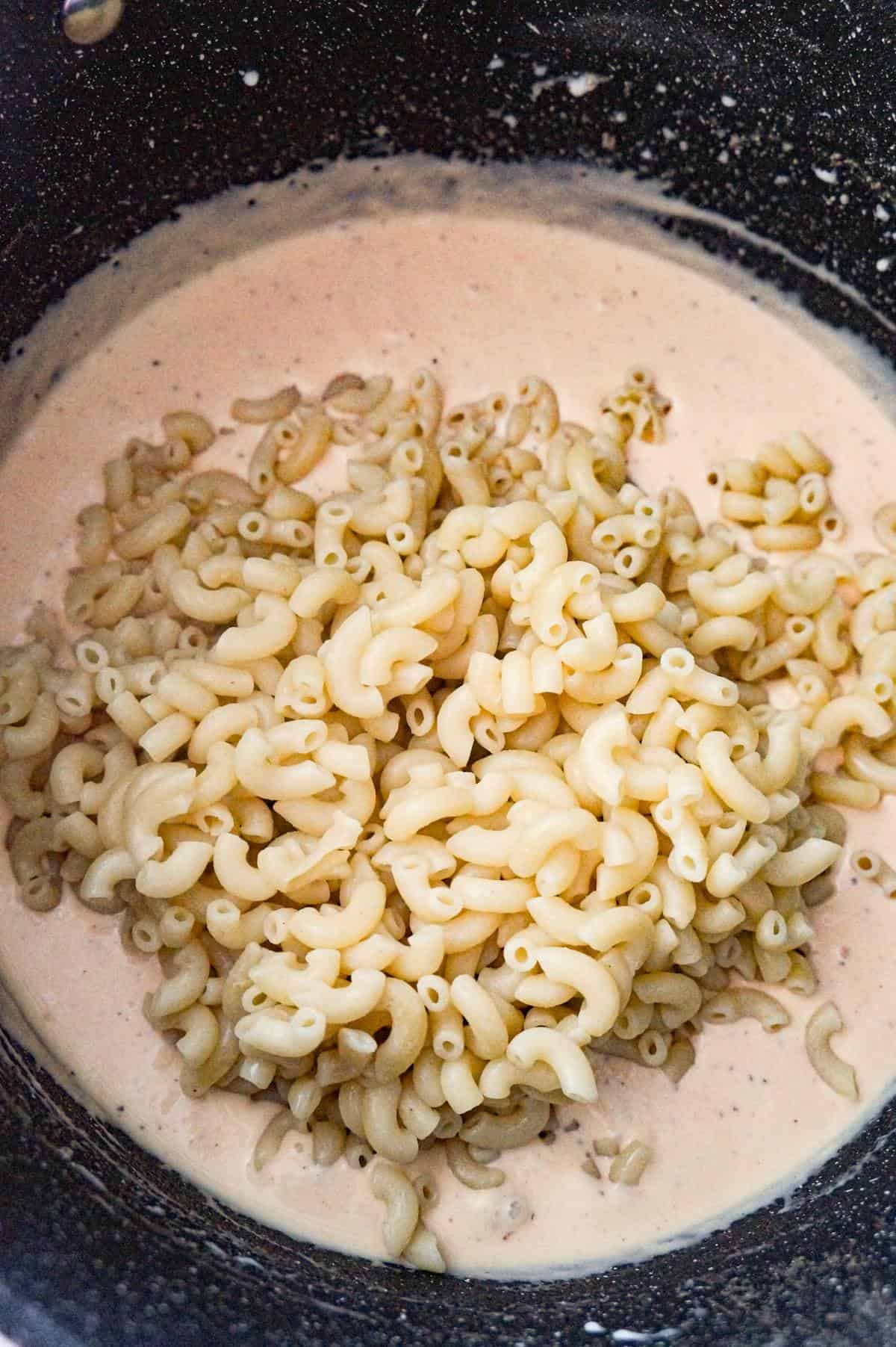 cooked macaroni on top of creamy sauce in a large pot
