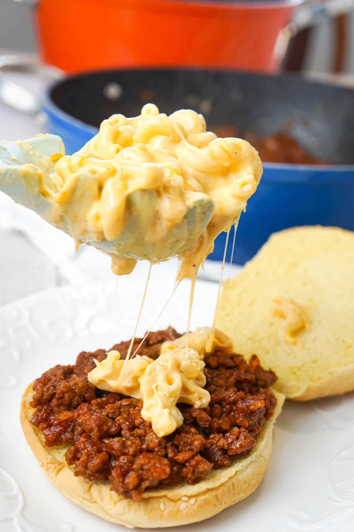 Mac and Cheese Sloppy Joes are hearty ground beef sandwiches topped with macaroni and cheese.