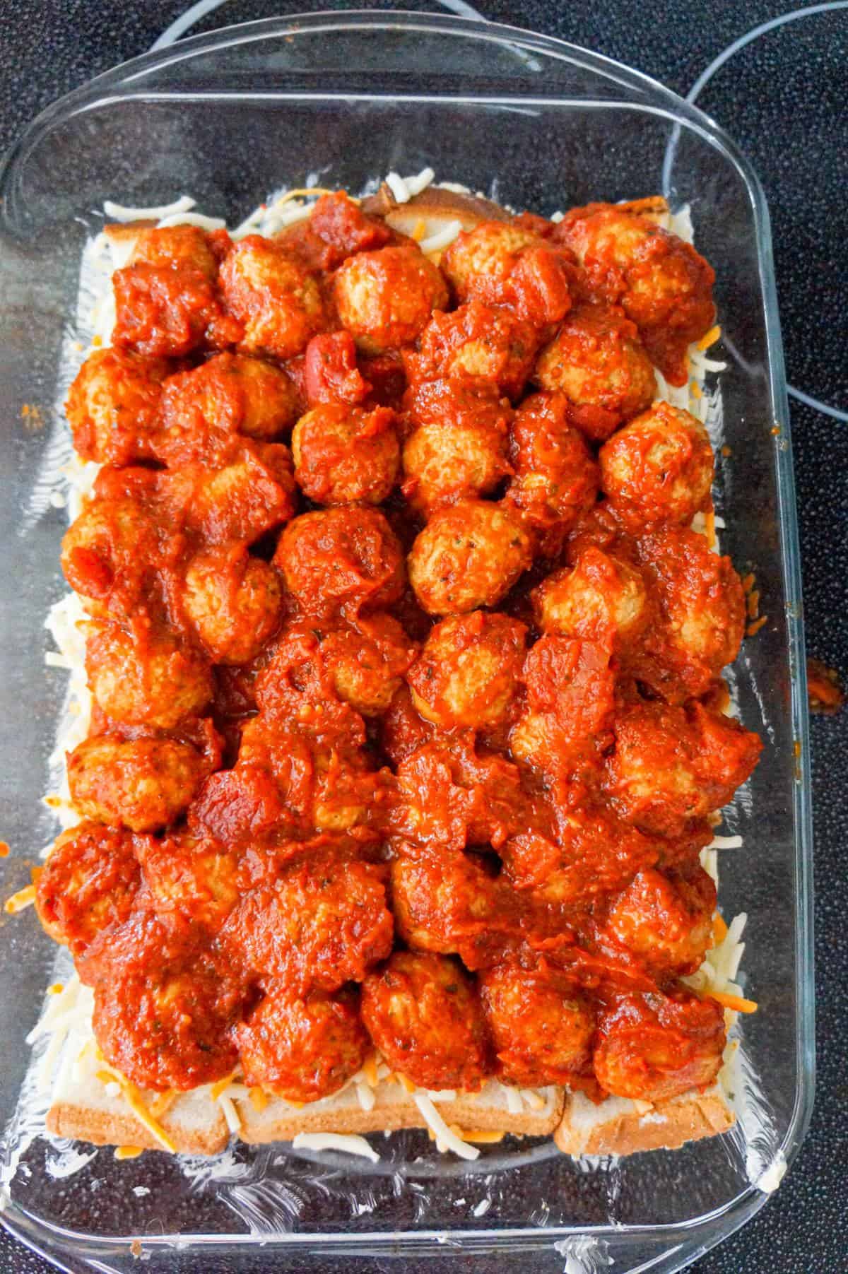 meatballs and marinara on top of cheese and bread in a baking dish