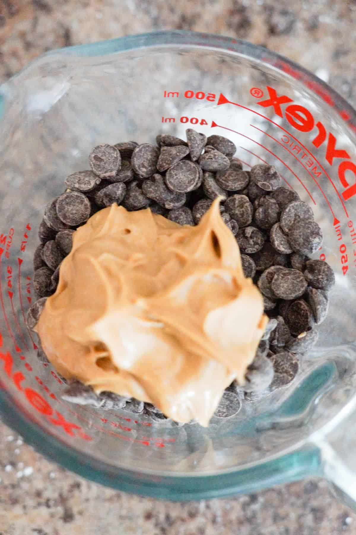 peanut butter on top of chocolate chips in a glass measuring cup