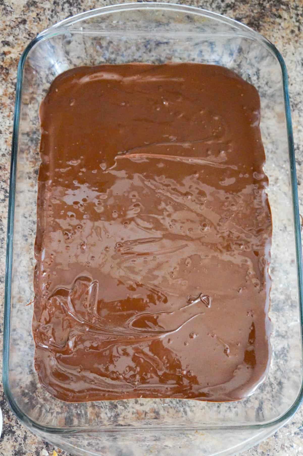 melted chocolate spread on top of peanut butter mixture in a baking dish