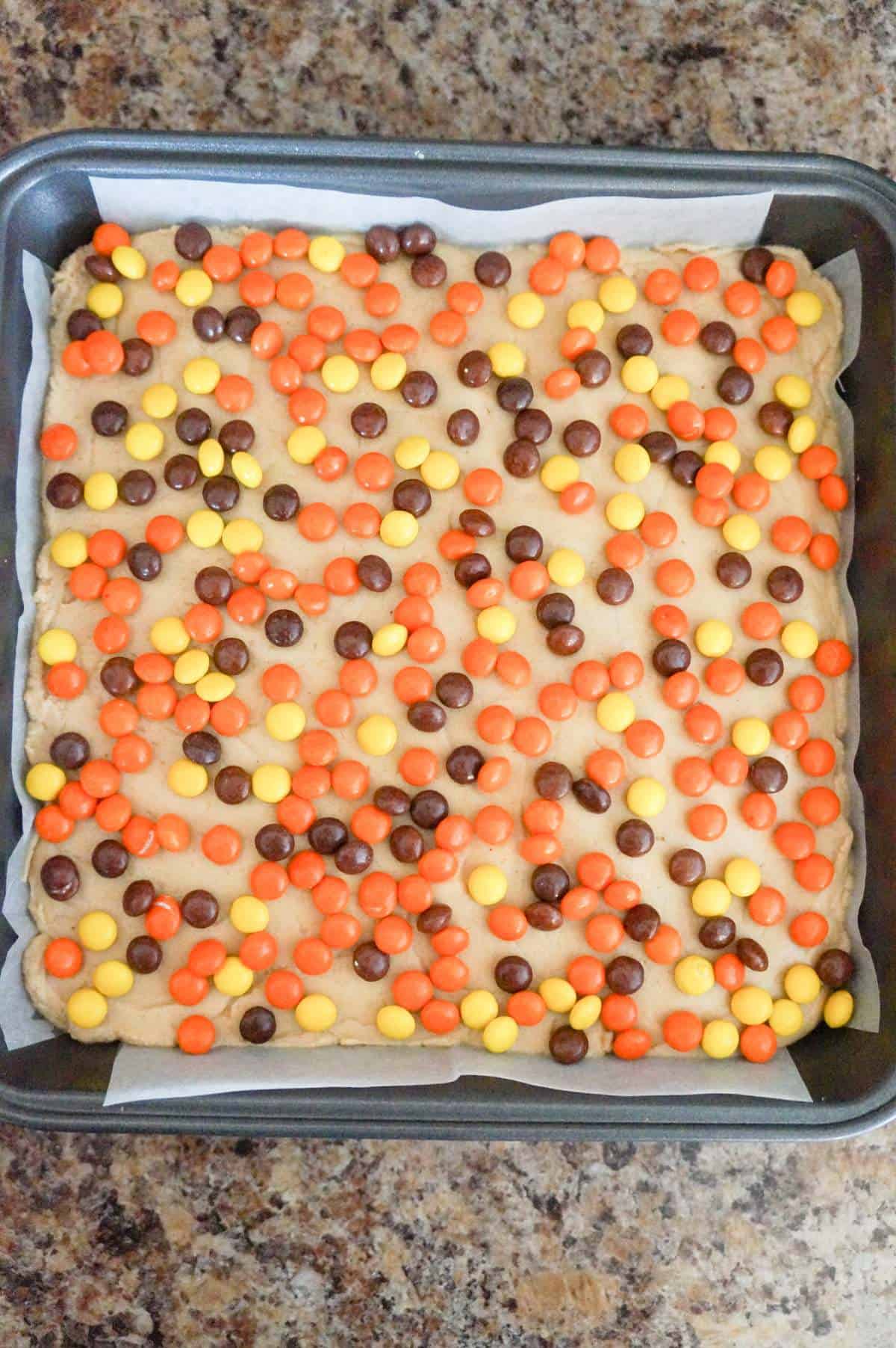 mini Reese's pieces on top of peanut butter fudge in a pan