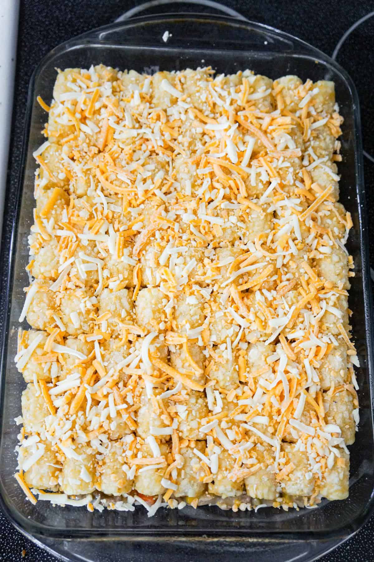 shredded cheddar cheese on top of tater tot casserole before baking