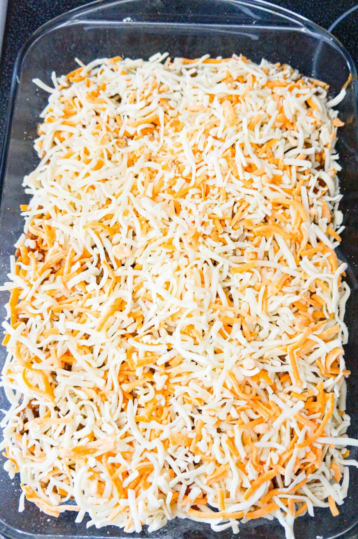 shredded cheese on top of ground beef casserole before baking