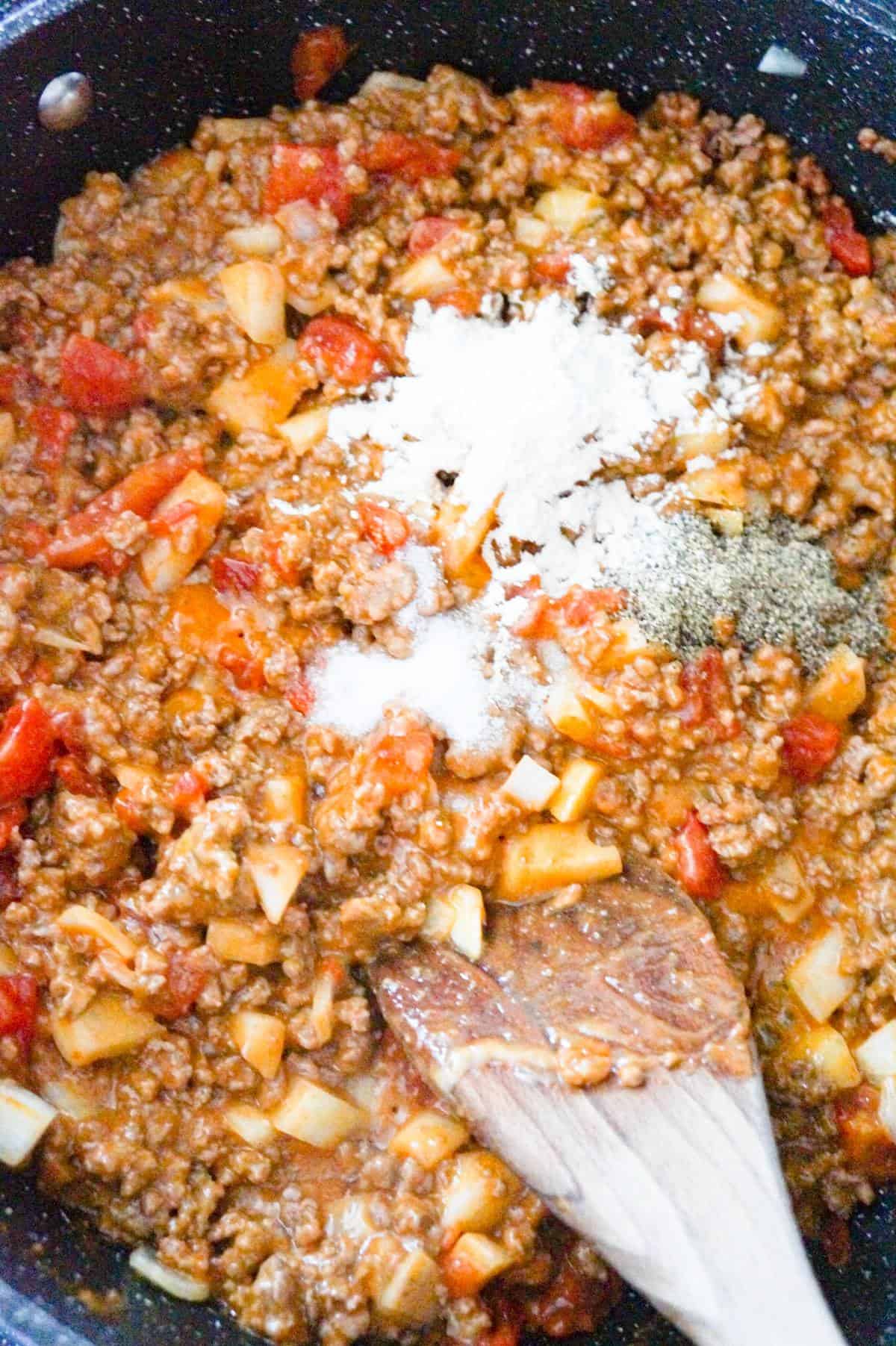 spices on top of cheese soup and ground beef mixture in a saute pan