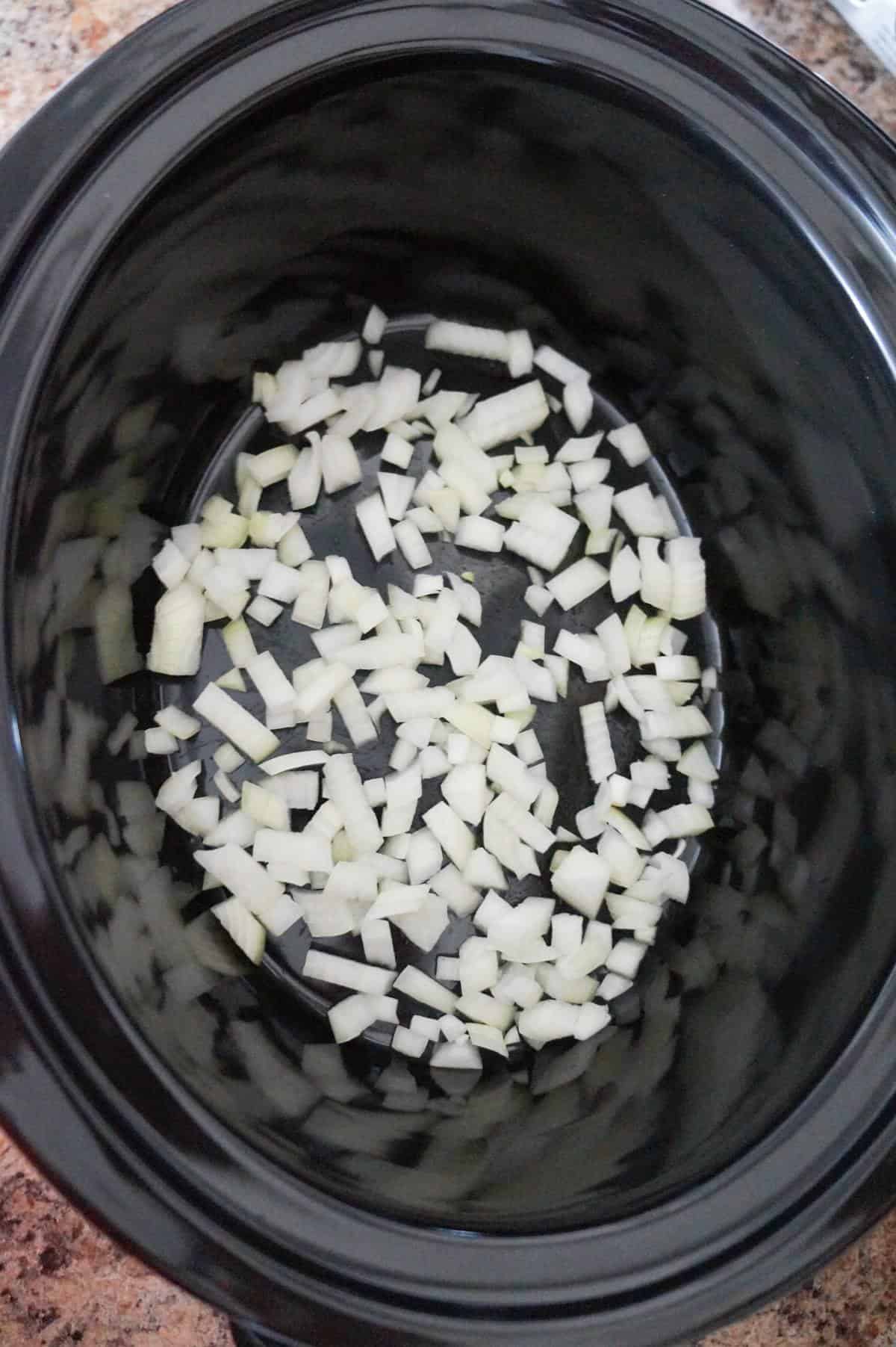 diced onions in the bottom of a crock pot