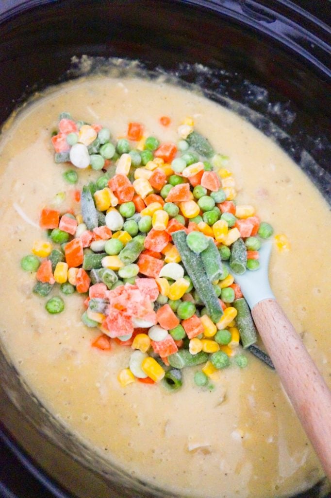 frozen vegetables on top of creamy chicken mixture in a slow cooker