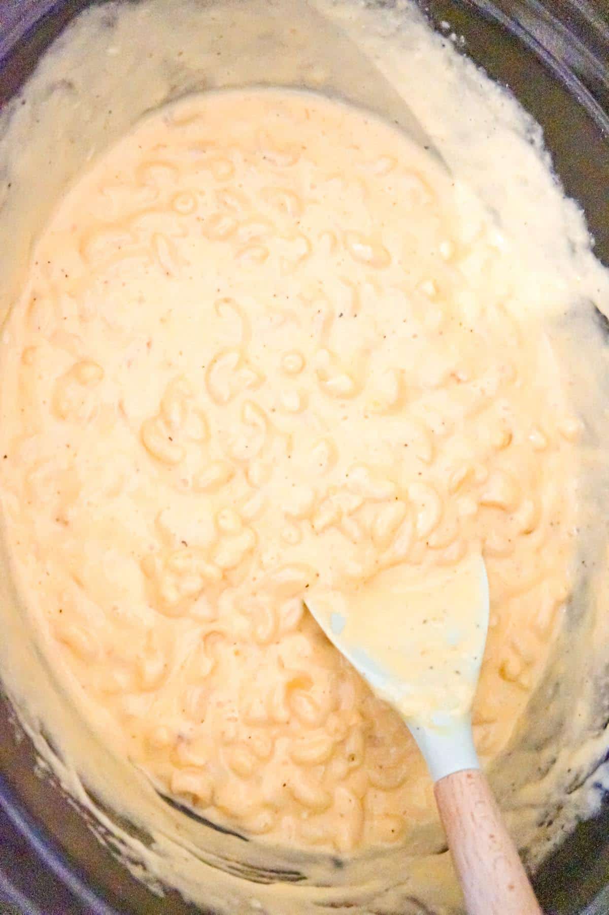 macaroni and cheese being stirred in a crock pot