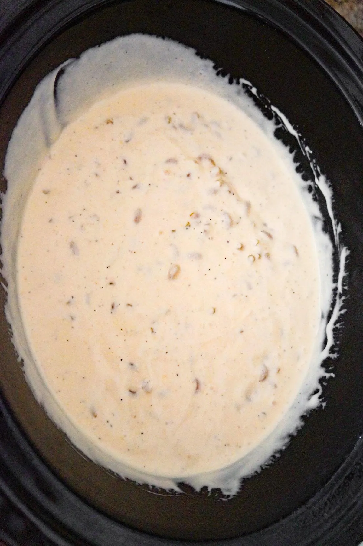 uncooked macaroni in a creamy cheddar soup mixture in a crock pot
