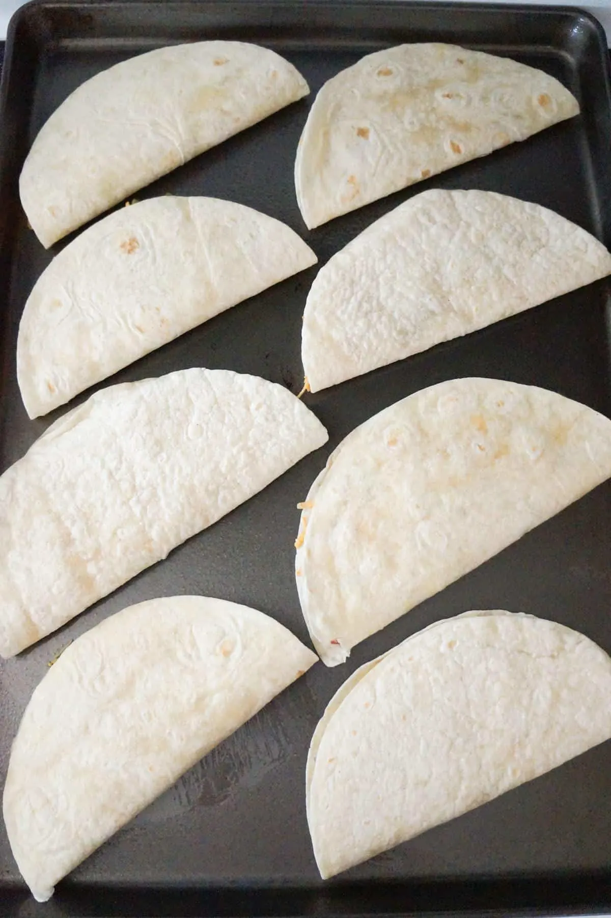 chicken quesadillas on a baking sheet before baking