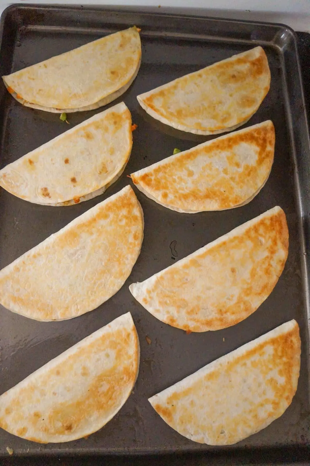 Easy Baked Chicken Quesadillas are a simple weeknight dinner recipe made with flour tortillas loaded with shredded chicken, taco seasoning, green peppers, red onions and cheese before baking in the oven.