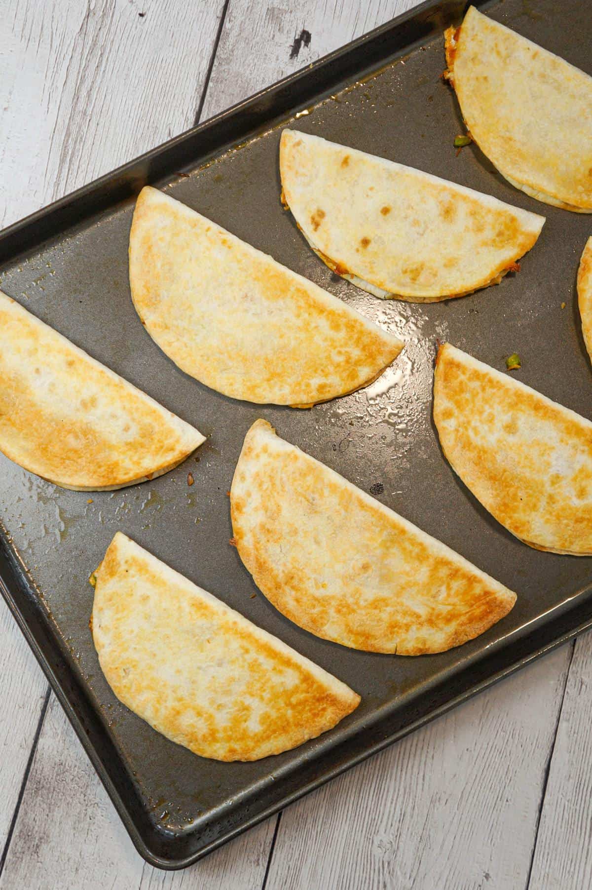 Easy Baked Chicken Quesadillas are a simple weeknight dinner recipe made with flour tortillas loaded with shredded chicken, taco seasoning, green peppers, red onions and cheese before baking in the oven.