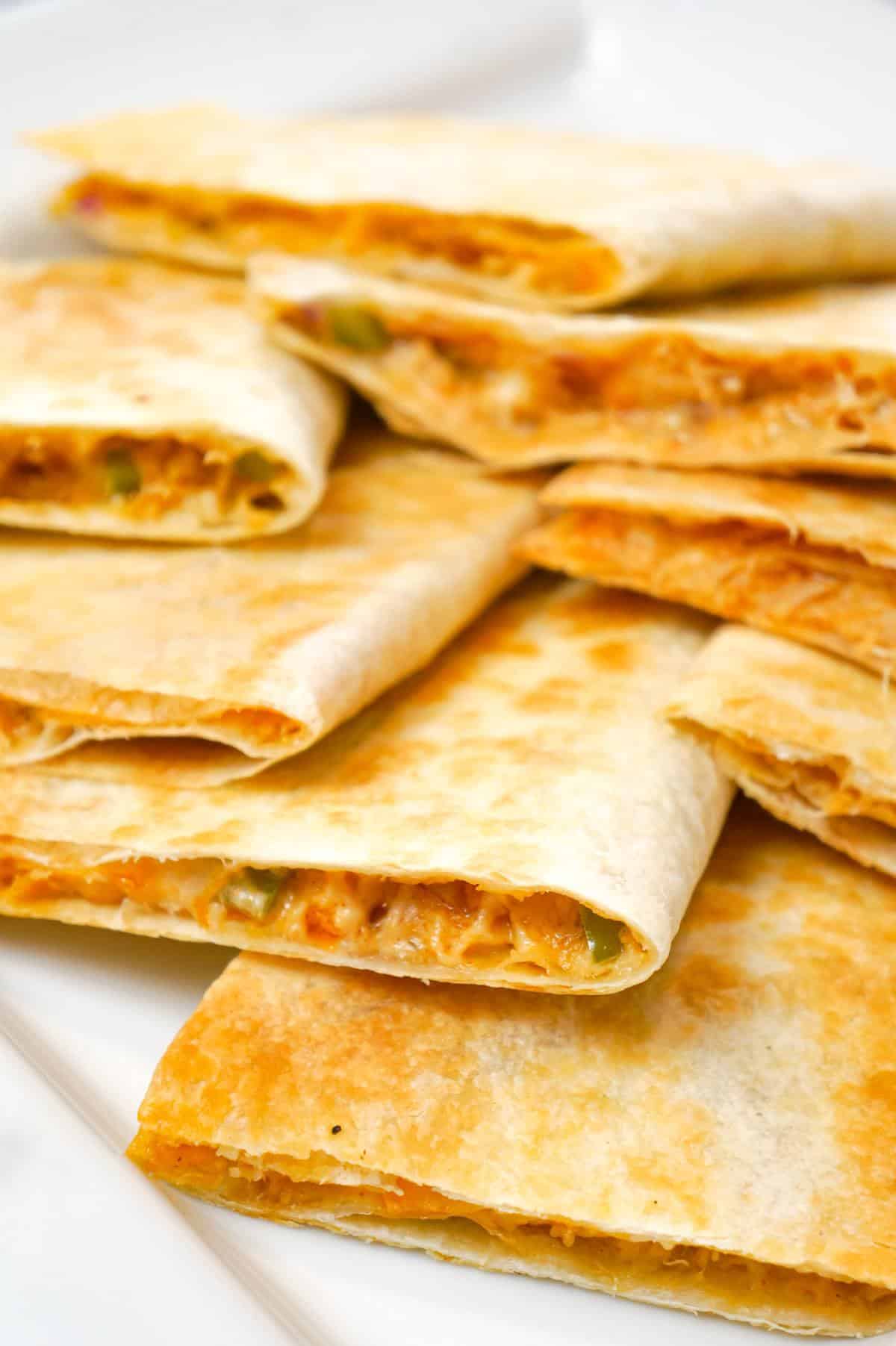 Easy Baked Chicken Quesadillas are a simple weeknight dinner recipe made with flour tortillas loaded with shredded chicken, taco seasoning, green peppers, red onions and cheese before baking in the oven.