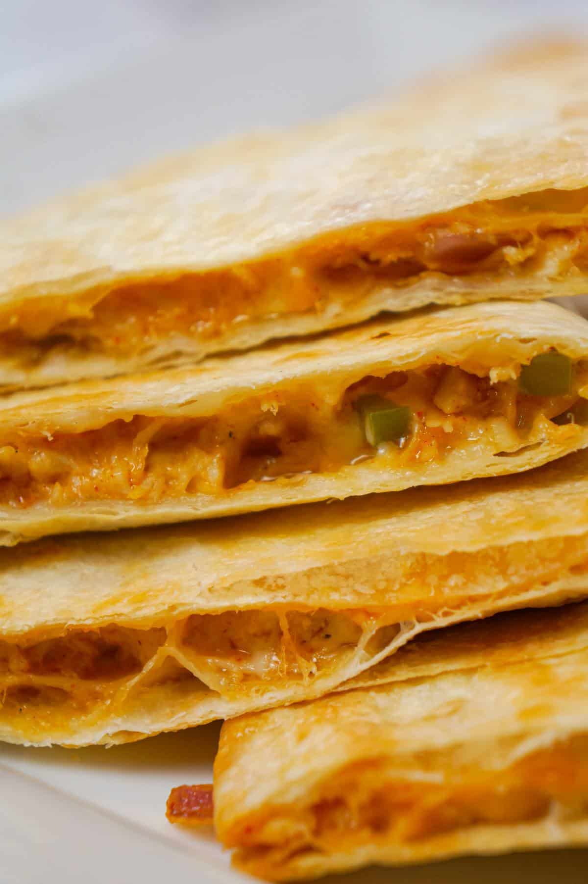 Easy Baked Chicken Quesadillas are a simple weeknight dinner recipe made with flour tortillas loaded with shredded chicken, taco seasoning, green peppers, red onions and cheese before baking in the oven.