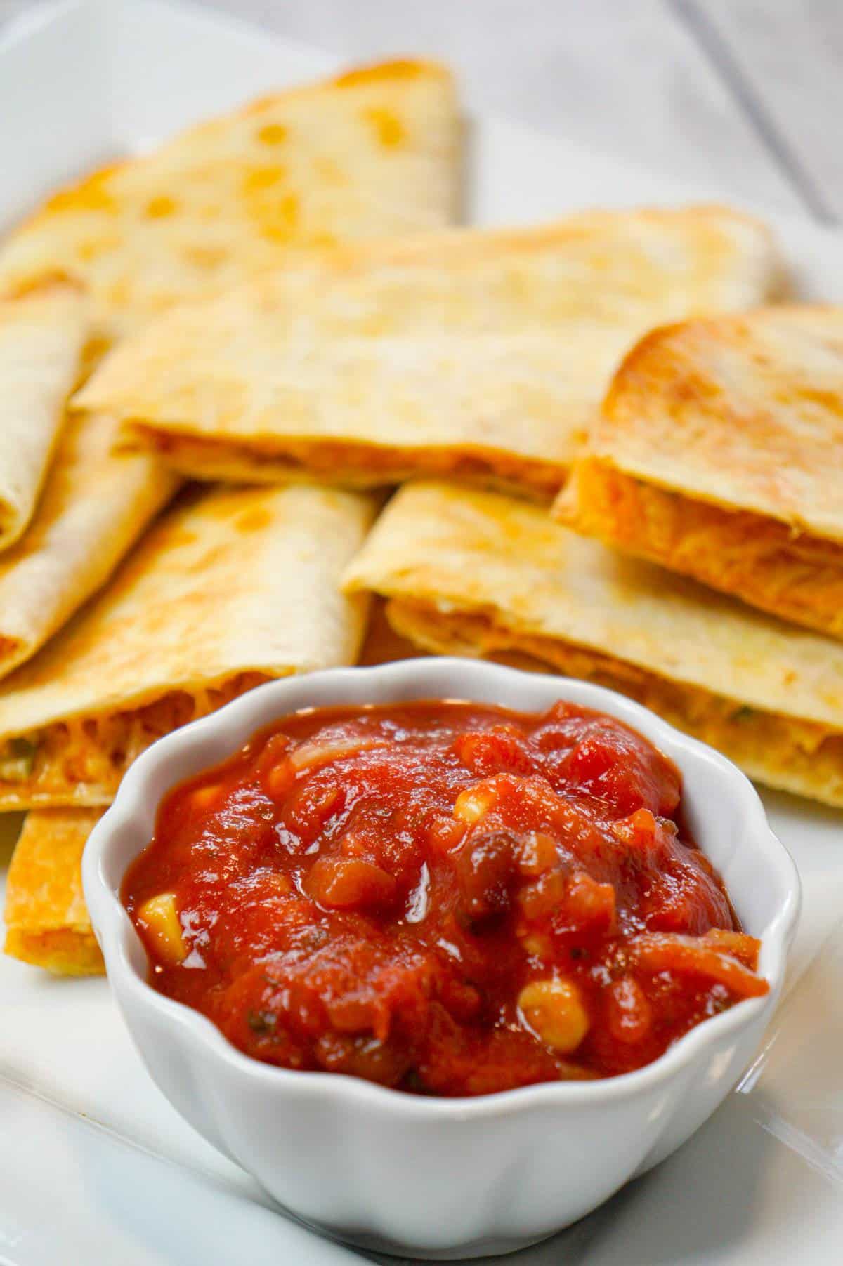 Easy Baked Chicken Quesadillas are a simple weeknight dinner recipe made with flour tortillas loaded with shredded chicken, taco seasoning, green peppers, red onions and cheese before baking in the oven.