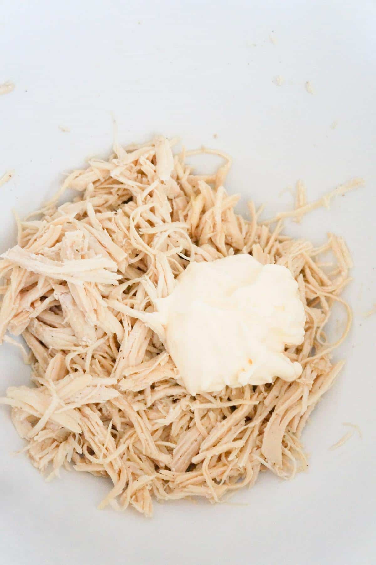 mayo on top of shredded chicken in a mixing bowl