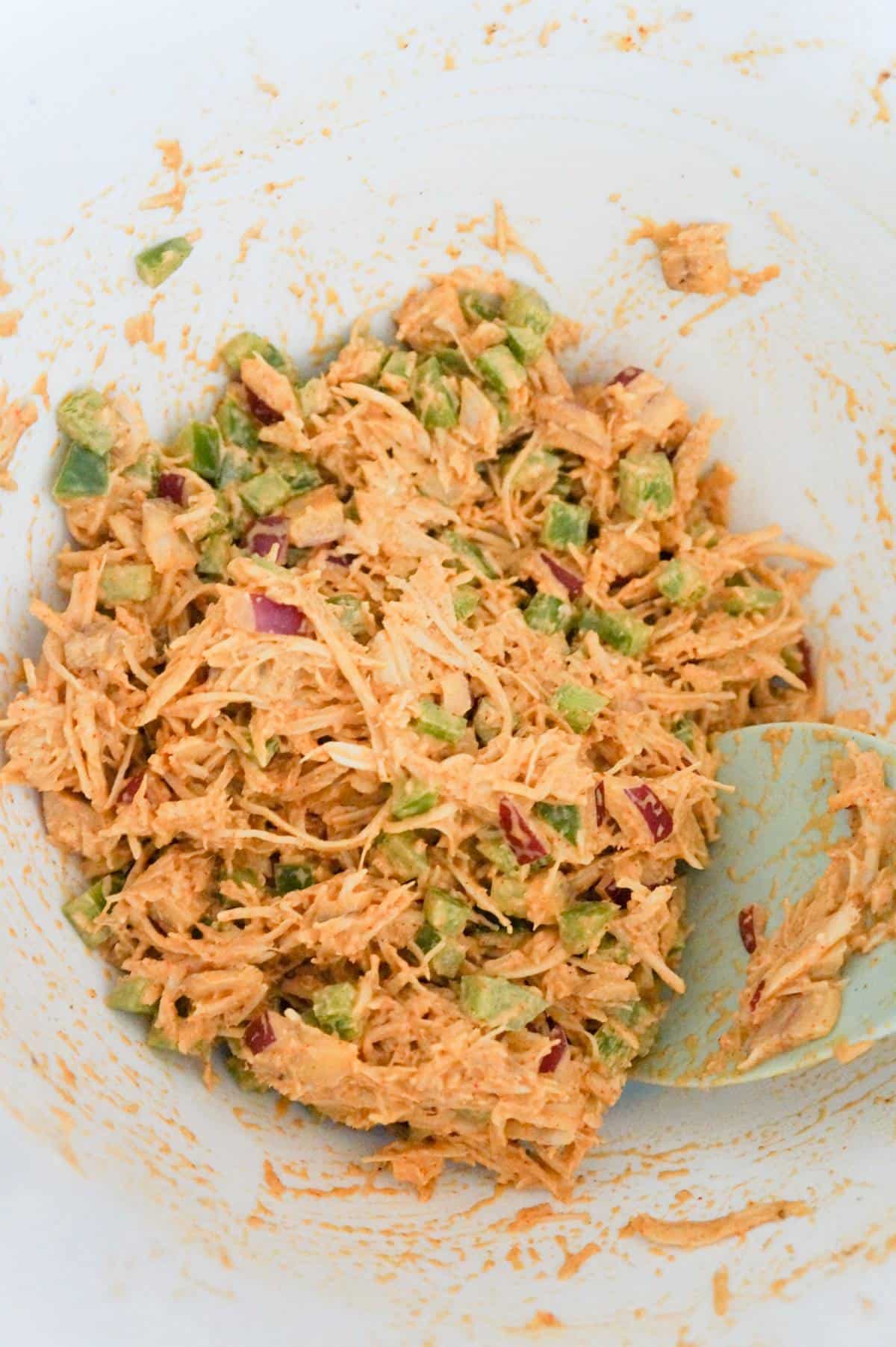shredded chicken mixture with diced onions and peppers in a mixing bowl