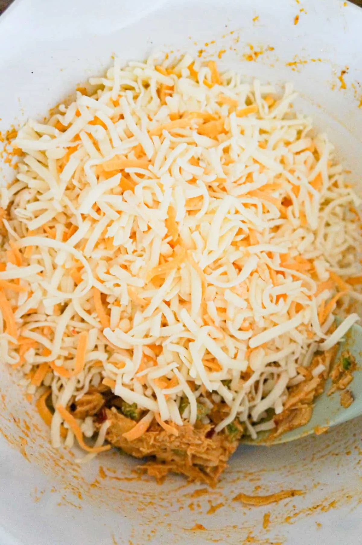 shredded cheese on top of chicken taco mixture in a mixing bowl