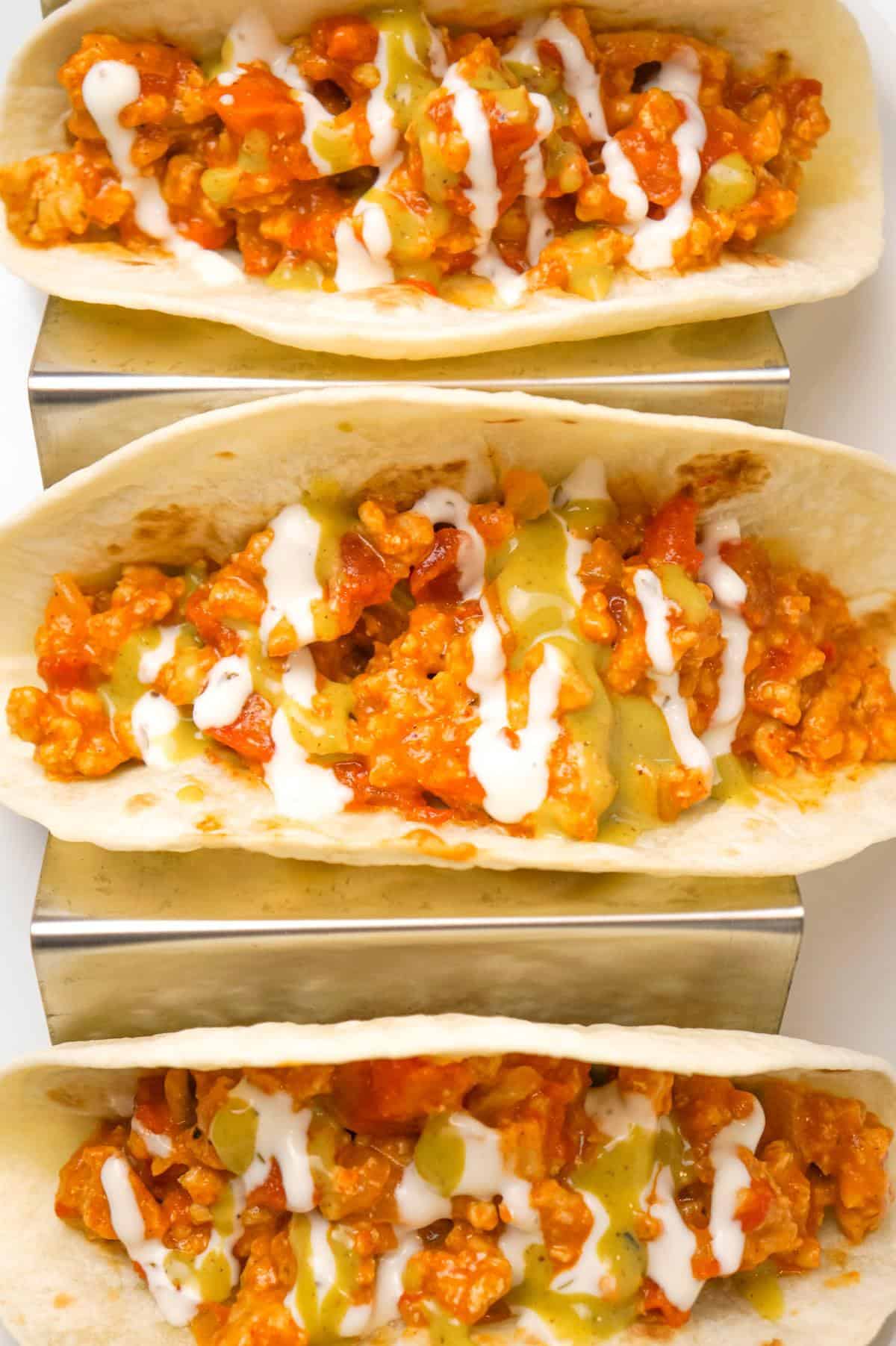 Ground Chicken Tacos are an easy weeknight dinner recipe made with lean ground chicken, chicken taco seasoning, Rotel diced tomatoes and green chilies and shredded cheese served in flour tortillas and drizzled with ranch and avocado dressing.