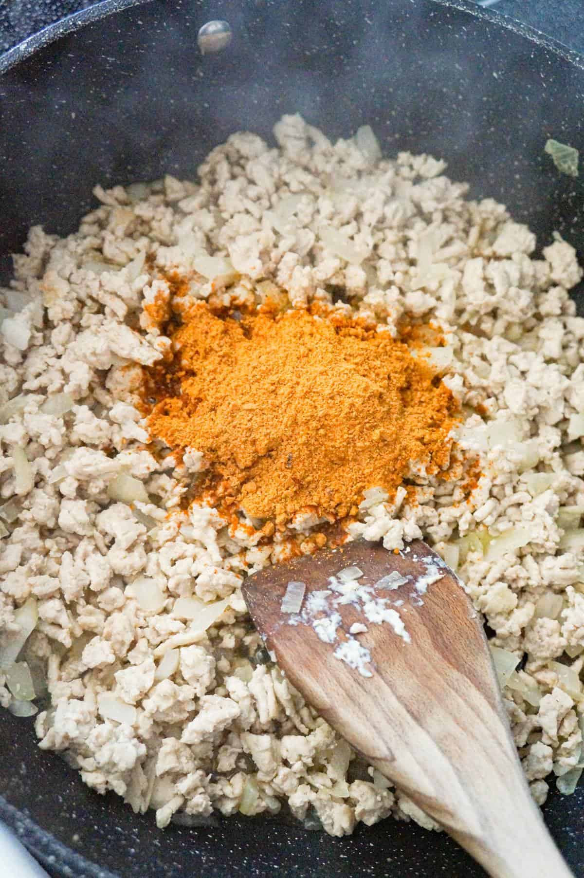 taco seasoning on top of cooked ground chicken in a saute pan